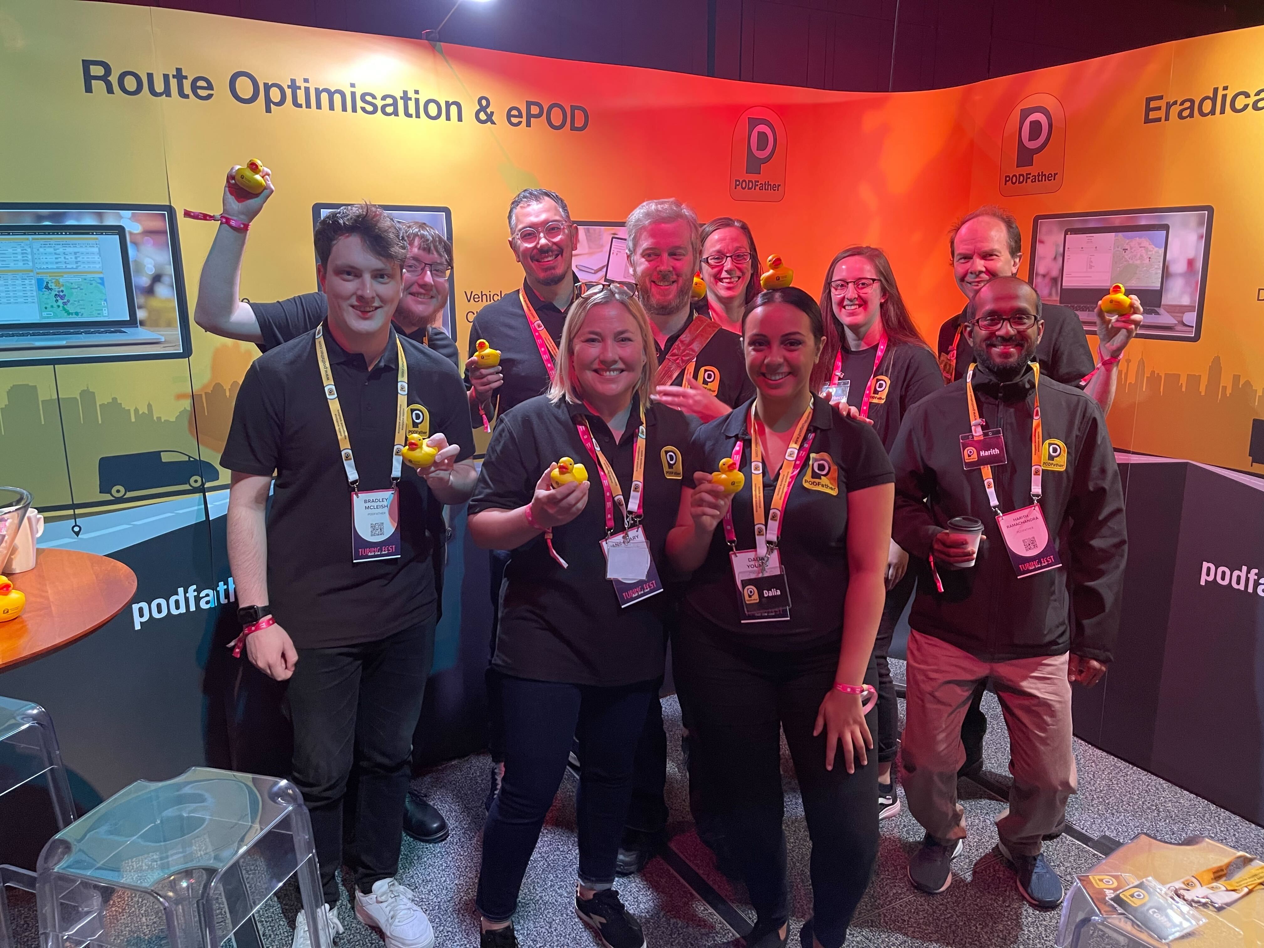 a group of people smiling in front of an exhibition stand