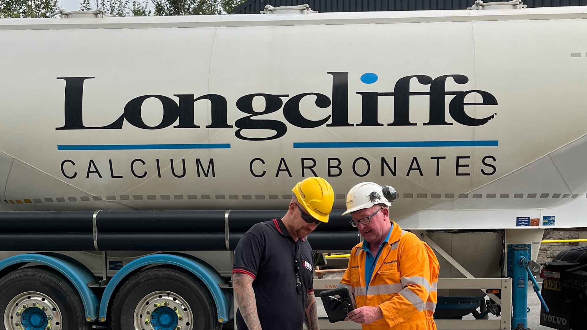Two Longcliffe employees infront of one of their vehicles holding a tablet