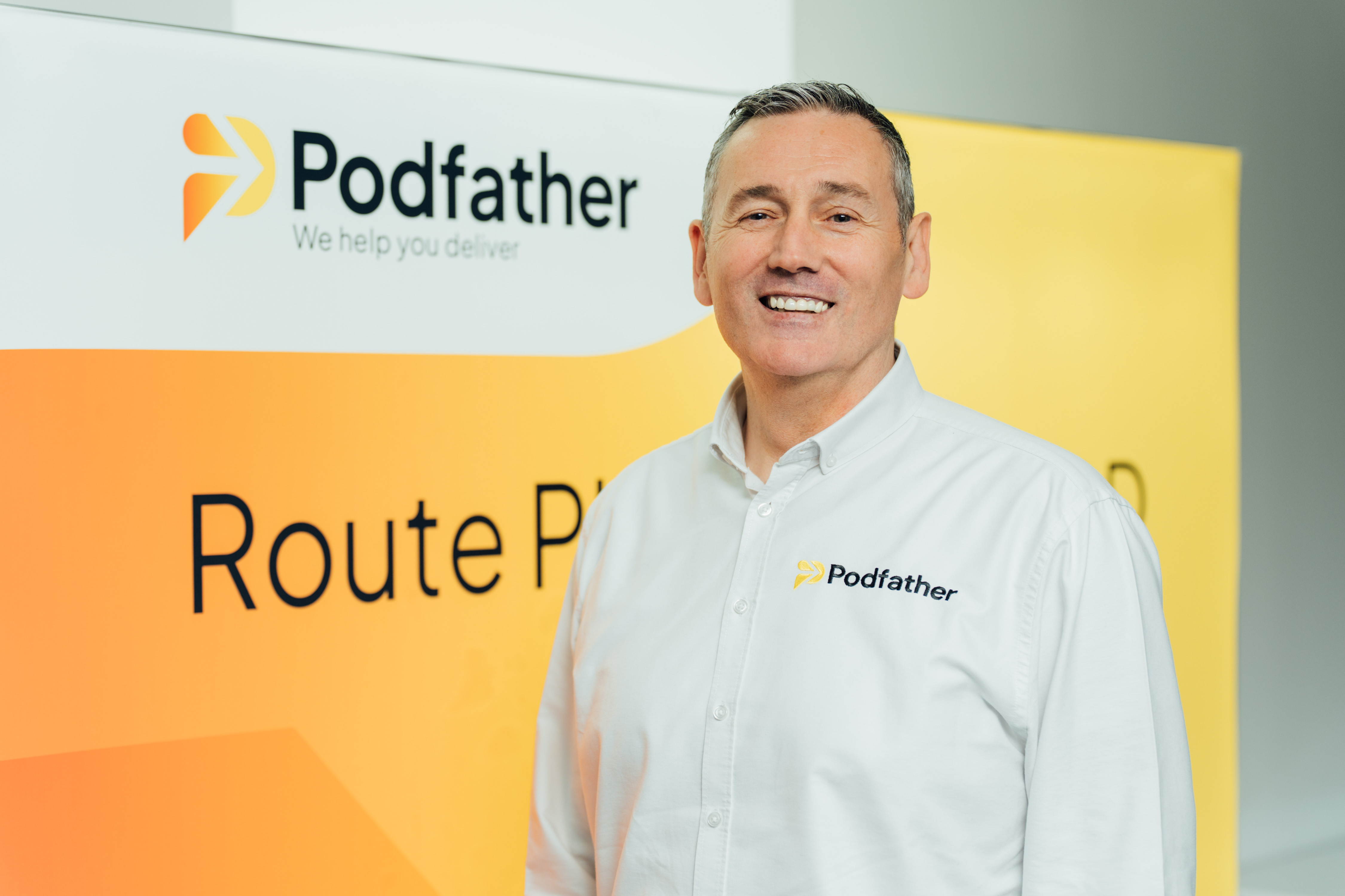 Picture of a man standing in front of a branded background