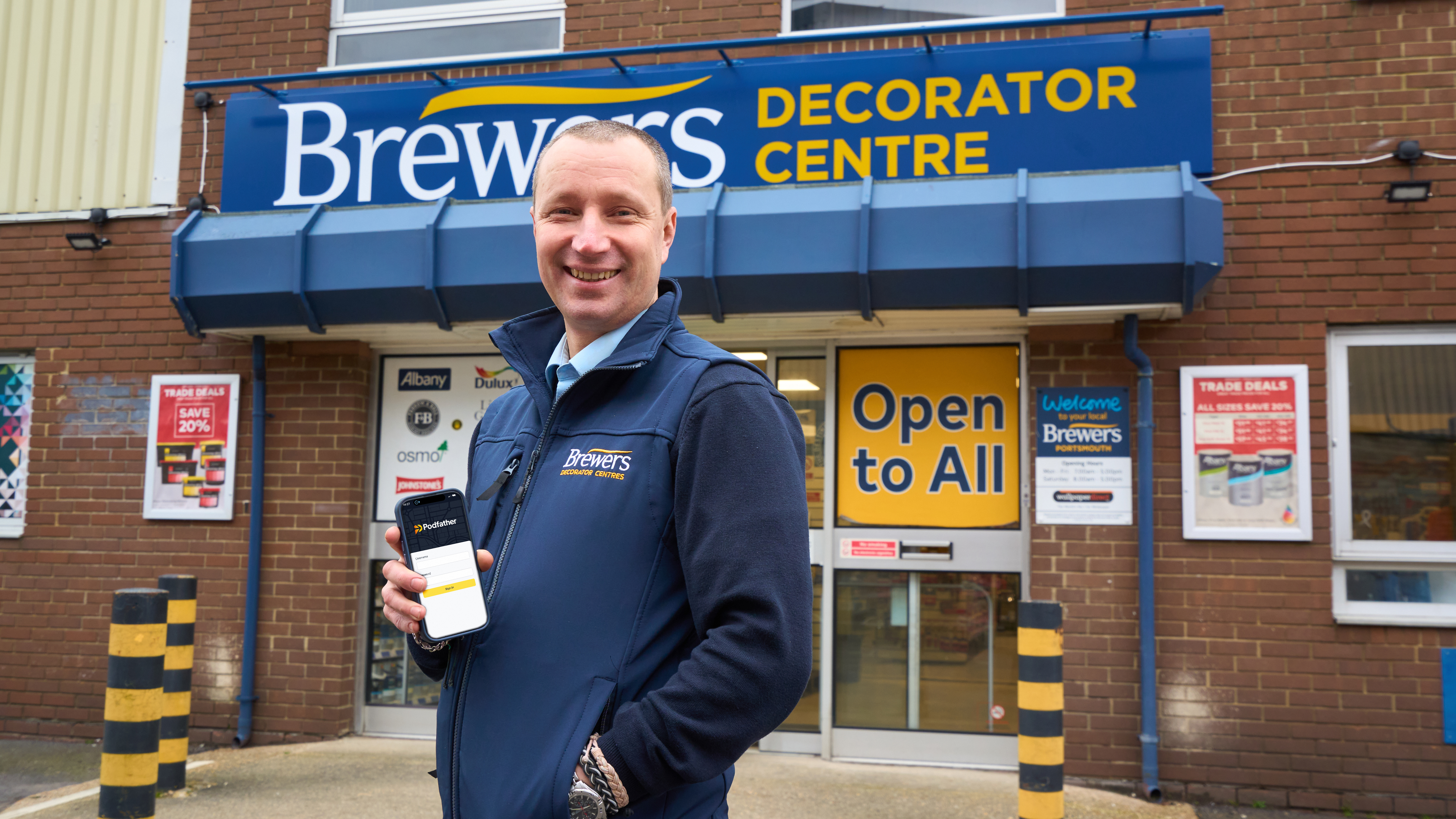 Man holding a mobile phone standing in front of a Brewers Decorator Store