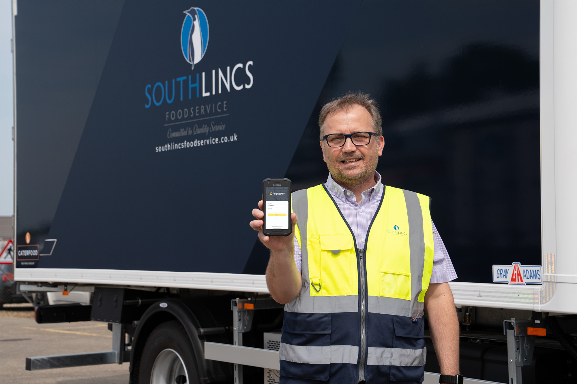 Man holding smartphone in front of lorry