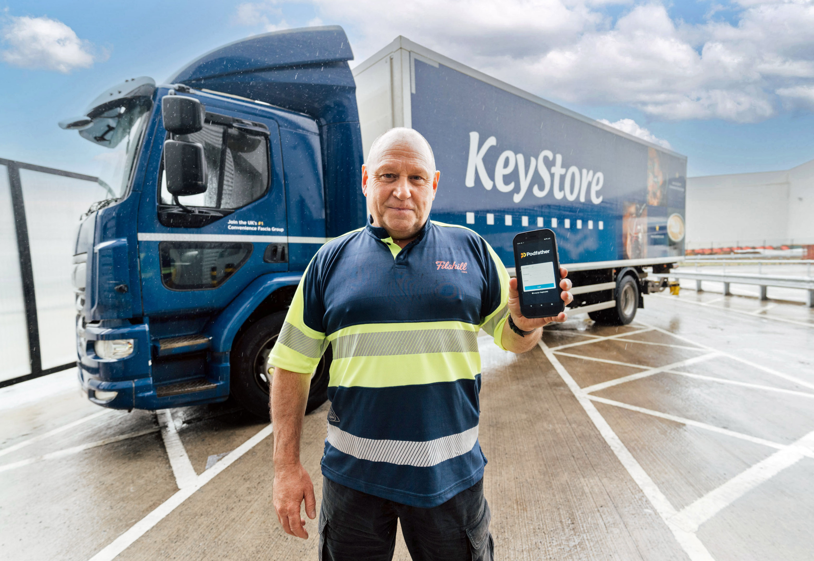 Man standing in front of lorry holding smartphone