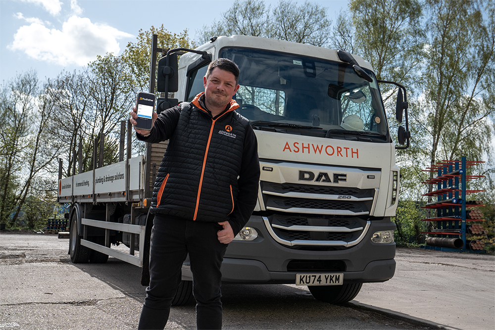 Man holding a mobile phone standing in front of a truck