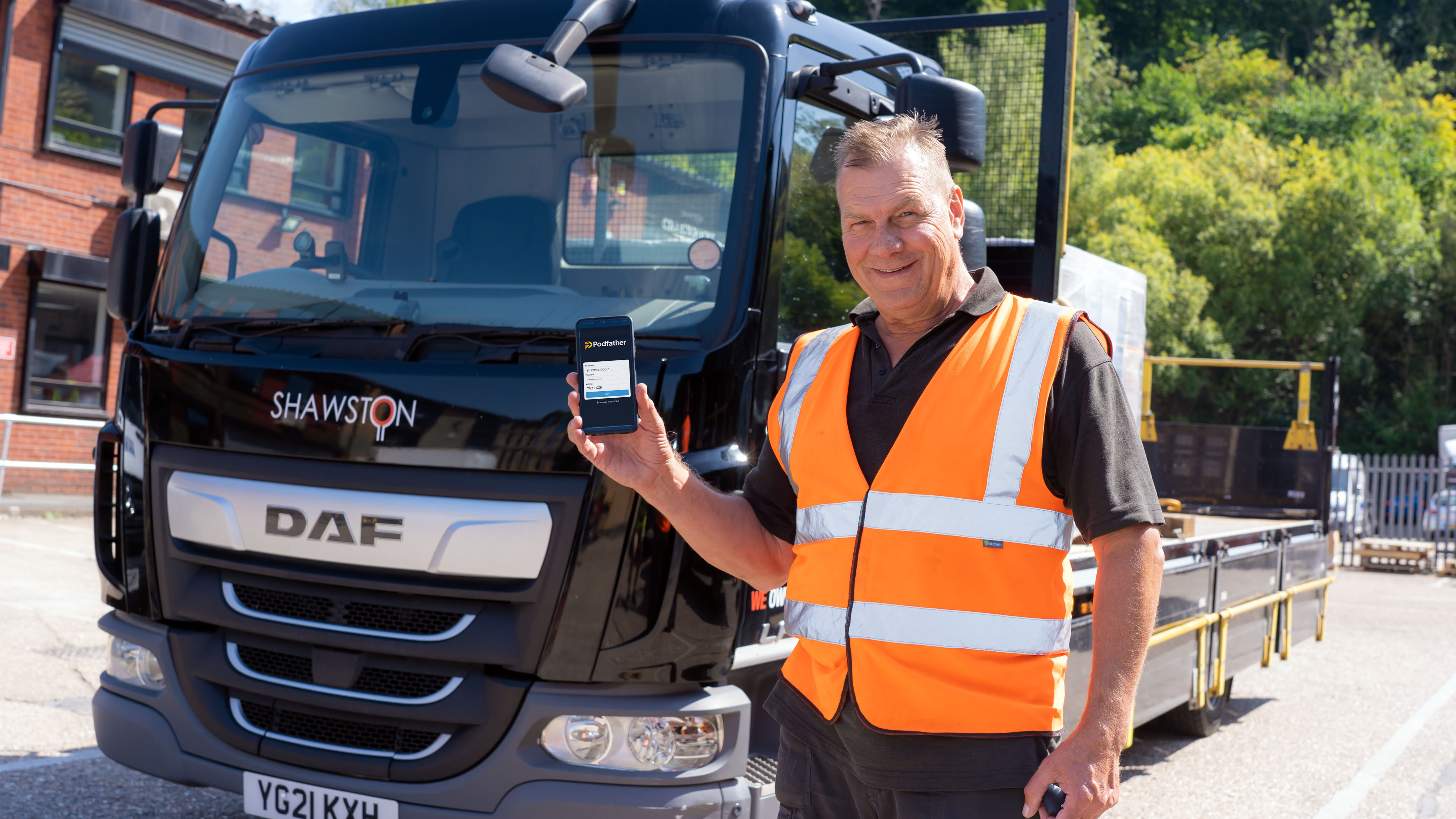 Man standing in front of lorry holding smartphone