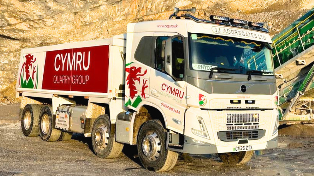 a white and dark red truck with a red dragon logo in a quarry