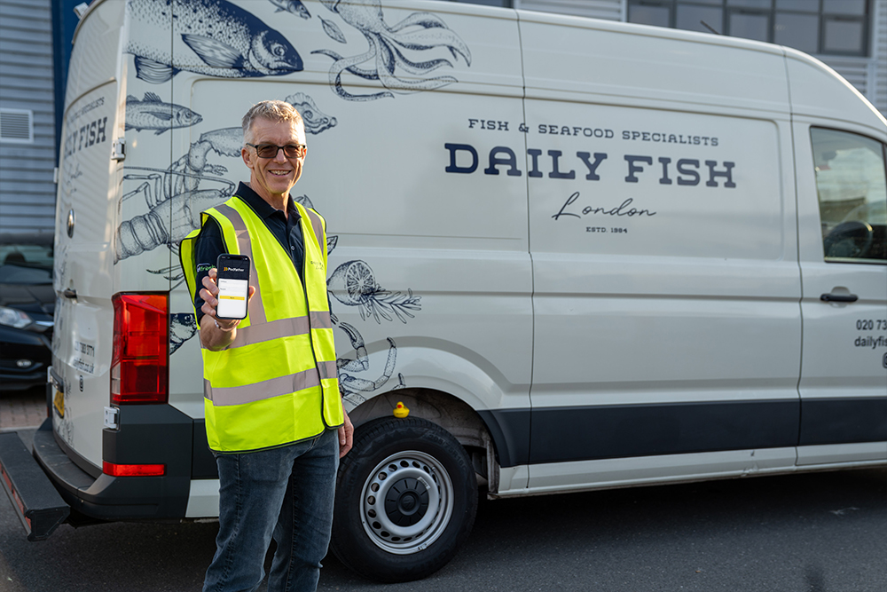Man in a yellow high vis vest standing infront of a Daily Fish branded van holding a mobile phone