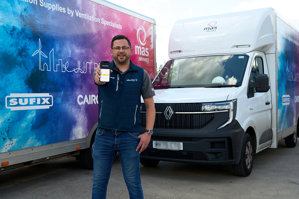 Man holding a mobile device standing in front of two vans