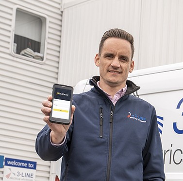 Smiling man in a navy jacket holding a mobile phone