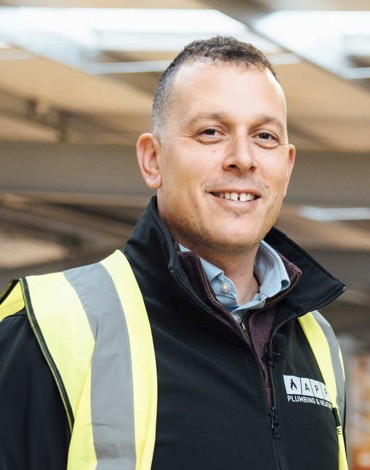 Smiling man wearing a jumper and a yellow high vis vest