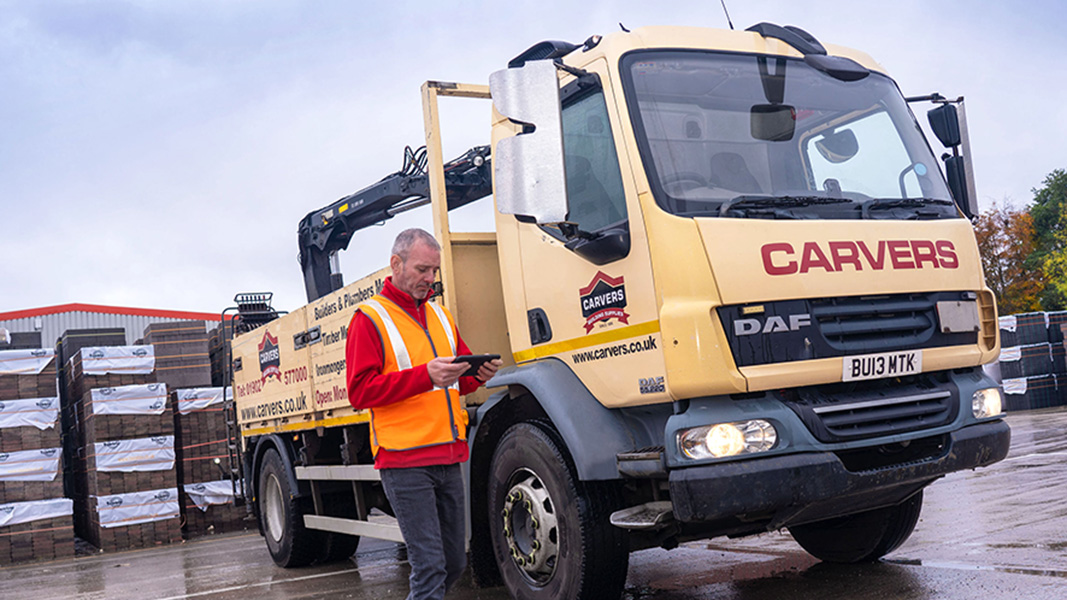 Man looking at a mobile device standing in front of a Carvers lorry