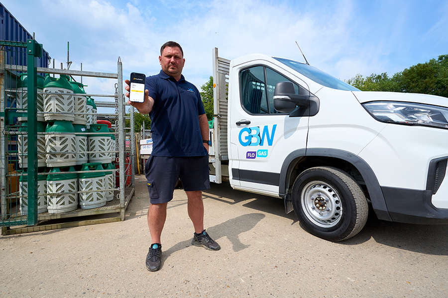 Man holding a mobile device standing in front of a Gas Bottles Wimbledon truck