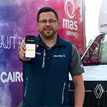 Man holding a mobile device standing in front of a MAS vehicle