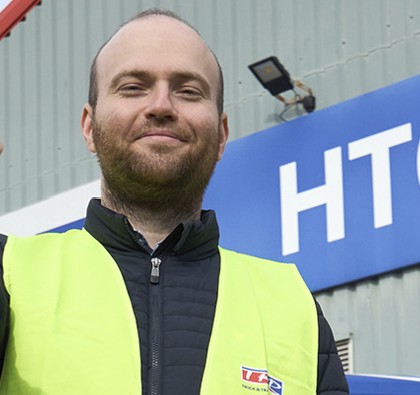 Smiling man in a blue jacket and yellow high vis vest