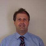 Man in a blue shirt and tie looking at the camera