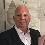 Smiling man looking at the camera wearing a dark suit and a white shirt