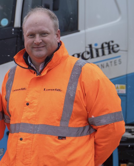 Smiling man wearing an orange high vis coat