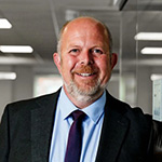 Smiling man wearing a dark suit smiling at the camera