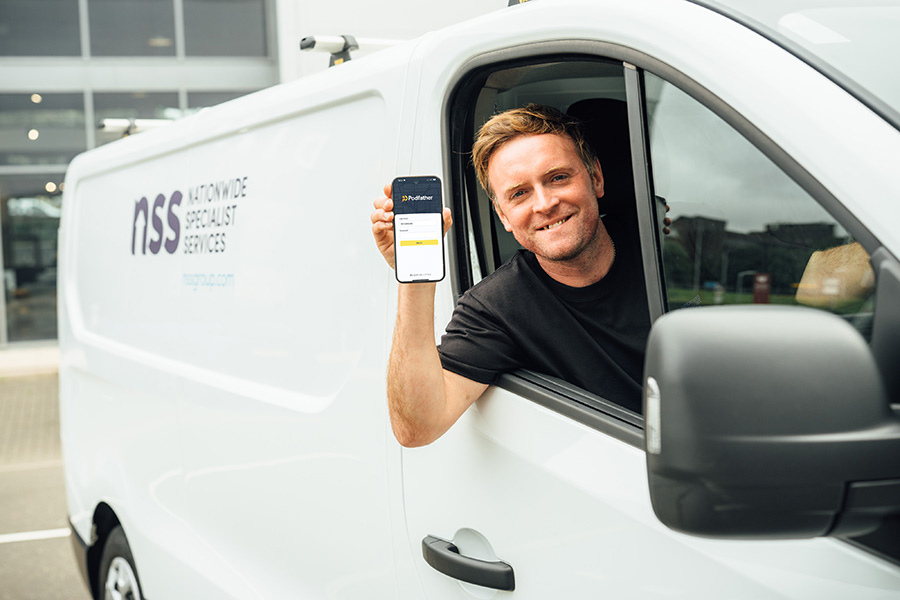 Smiling man sitting in a NSS van holding a mobile device