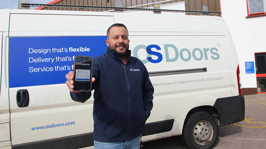 Man holding a phone standing in front of an OS Doors van