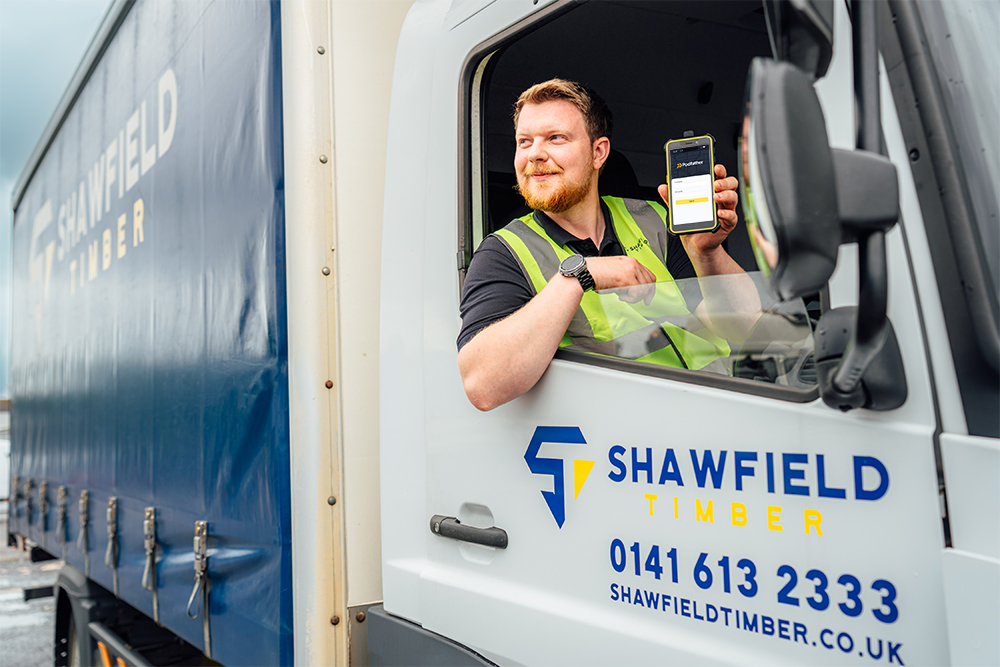 Man in a Shawfield Timber truck holding a mobile device