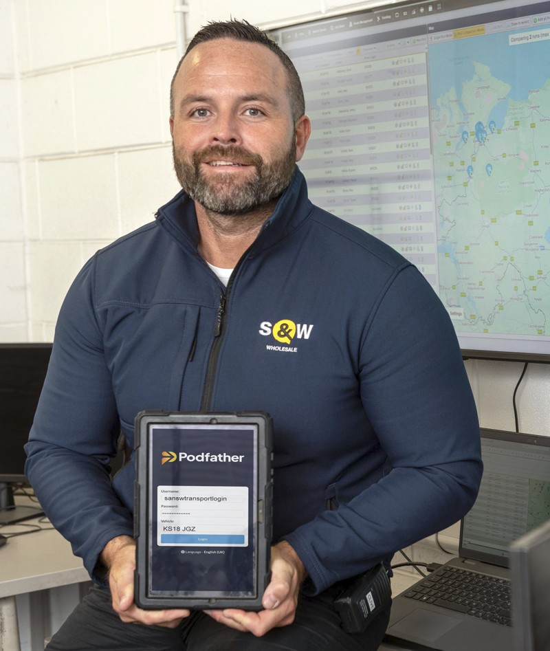 Smiling man looking at the camera holding a mobile device