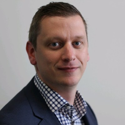 Man looking at the camera wearing a checked shirt and blue suit jacket