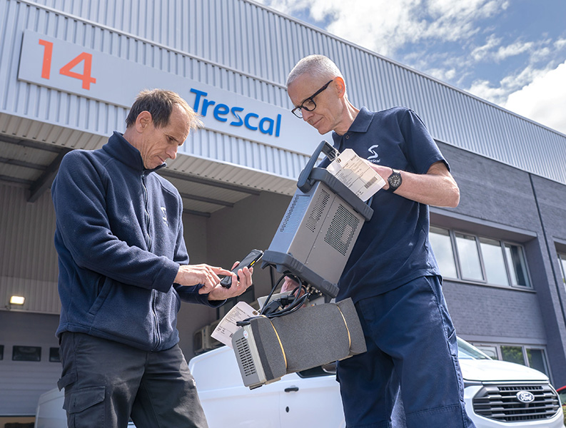 Two men holding a device standing in front of the Trescal office