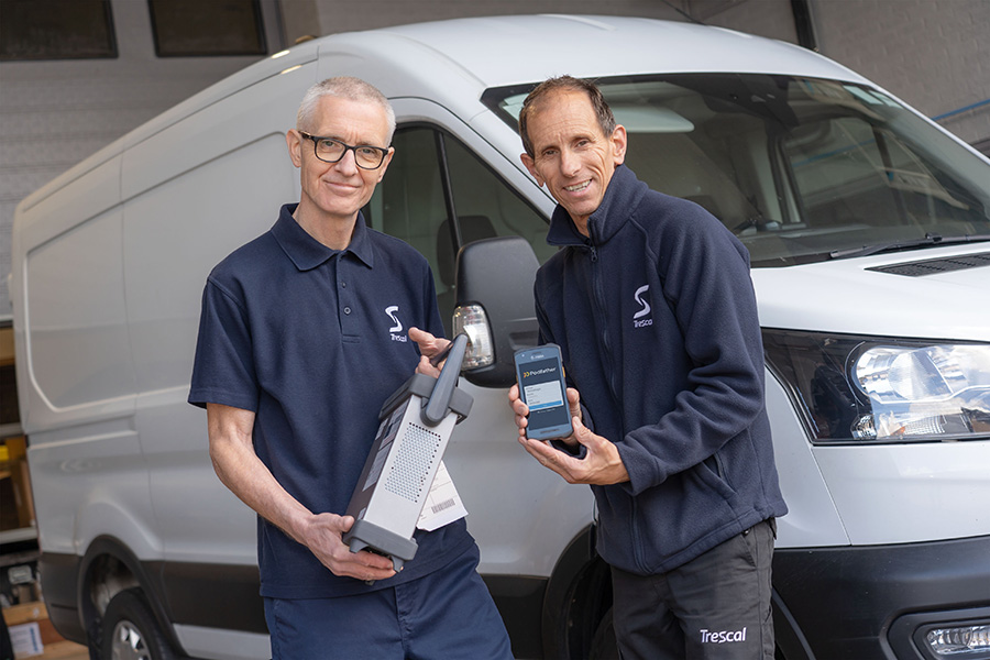 Two men looking at the camera standing in front of a van